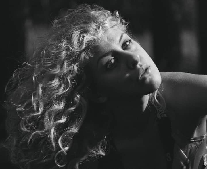Dramatic black and white portrait capturing a woman's fierce gaze and curly hair.