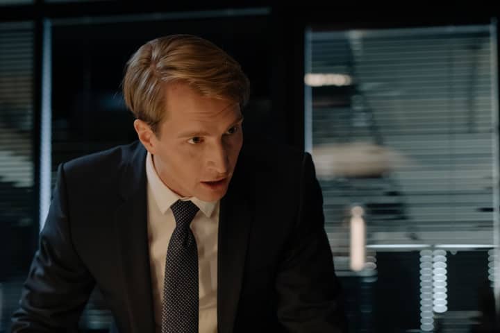 Focused businessman in a suit engaged in a serious discussion indoors with dramatic lighting.