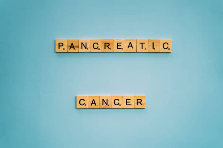 Wooden tiles spelling pancreatic cancer on blue. Health awareness concept.