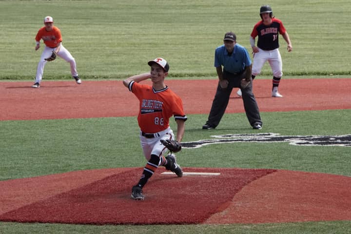 Pitcher in action during a high school baseball game on a sunny day.