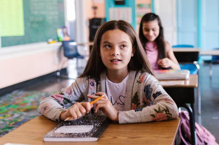 Two students attentively participate in a classroom environment, showcasing a back-to-school theme.