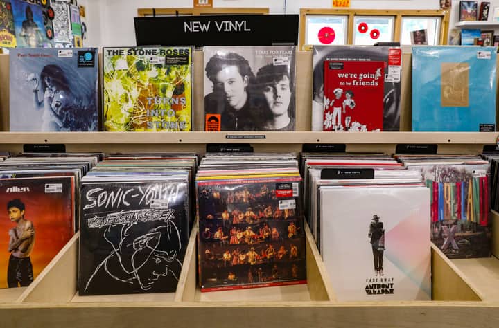 Explore a vibrant collection of new vinyl records in a Tulsa record store's wooden shelves.