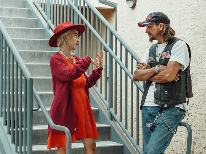 Casual conversation between a stylish woman and a man on outdoor stairs.