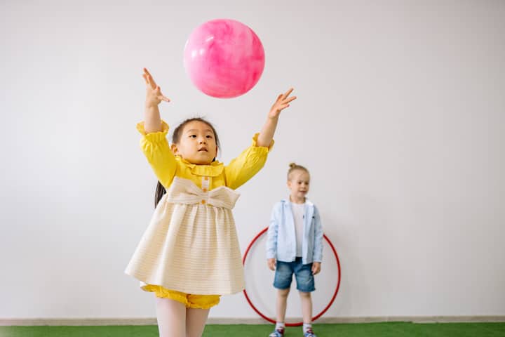 Two children enjoying playtime with balloons in a bright indoor setting.