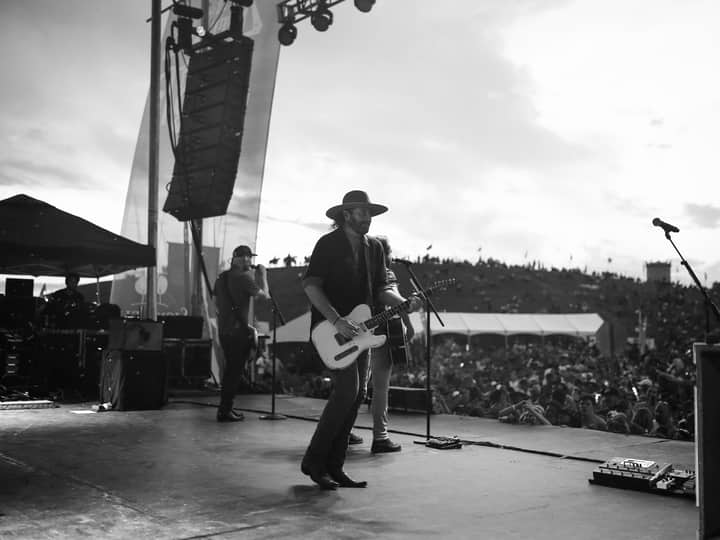 Black and white image of a live music performance with a crowd at an outdoor concert.