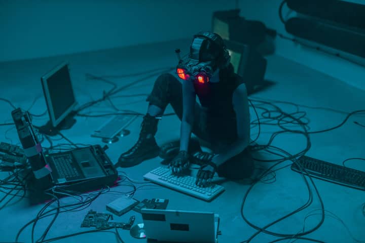 A woman in VR gear surrounded by computers and cables, immersed in a virtual simulation.