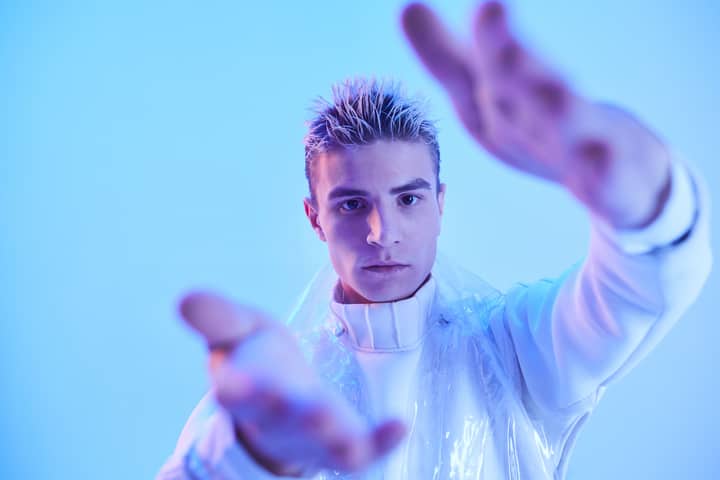 Dynamic fashion portrait of a male model posing in dramatic blue lighting.
