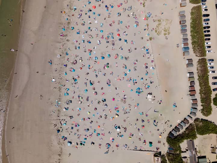A bird's eye view of West Wittering beach in England, bustling with people on a sunny day.
