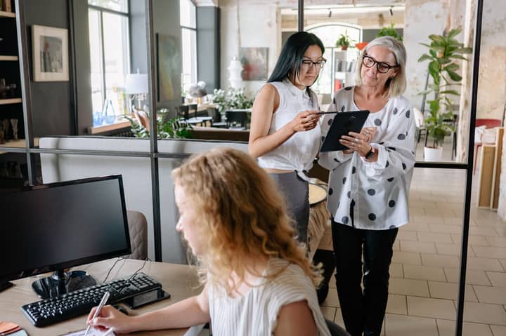 Professional women collaborating in a stylish office environment with tablets and computers.
