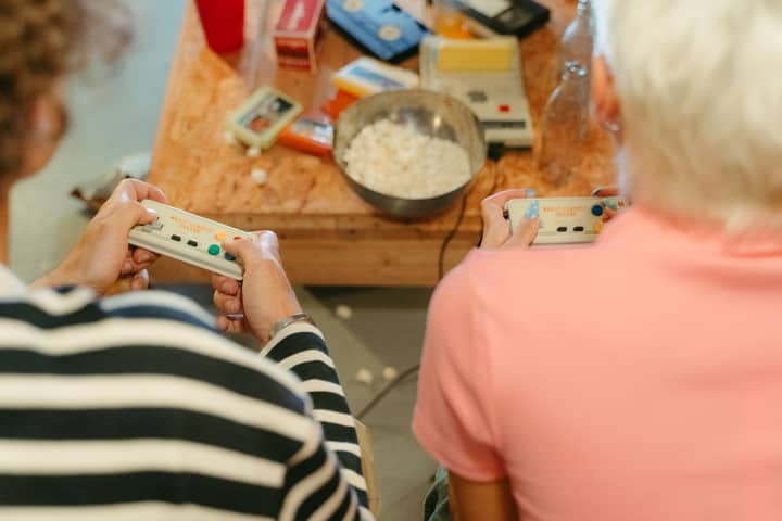 Two teenagers play video games together with snacks, creating a fun indoor atmosphere.