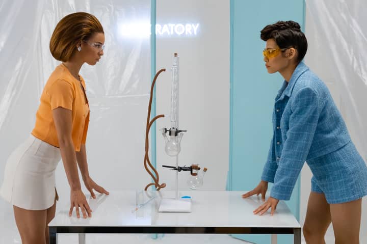 Two women in fashionable attire conducting an experiment in a modern laboratory.