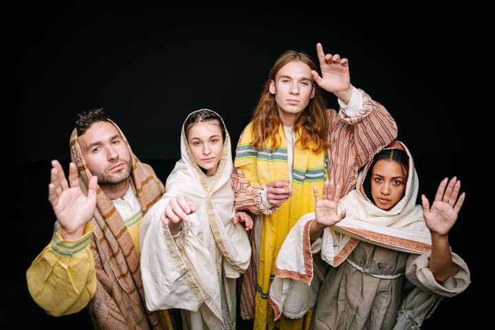 A group of actors in traditional religious costumes performing a dynamic theater scene.