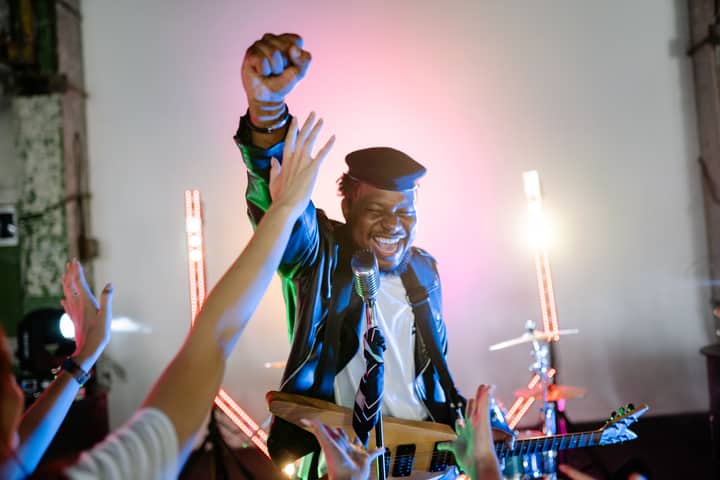 Vibrant live music performance by a band, showcasing a joyful lead guitarist with audience interaction.