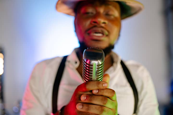 Close-up of a male singer holding a vintage microphone in a studio setting.