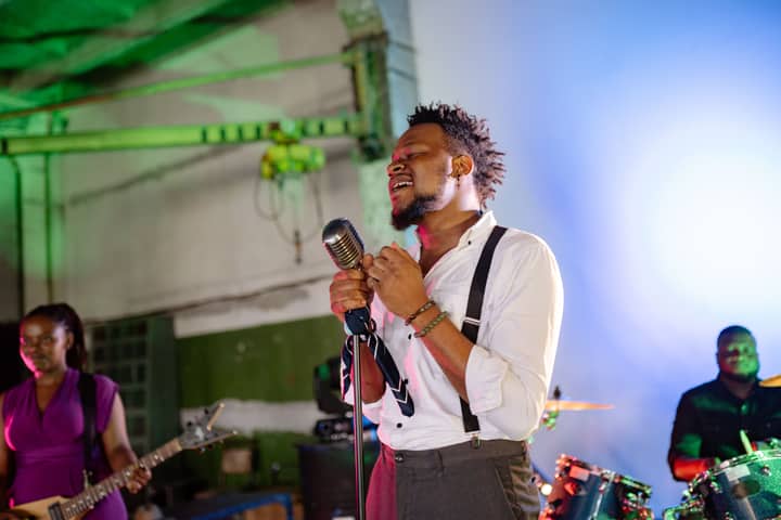 A vibrant music band performing energetically on an indoor stage with vivid lighting.
