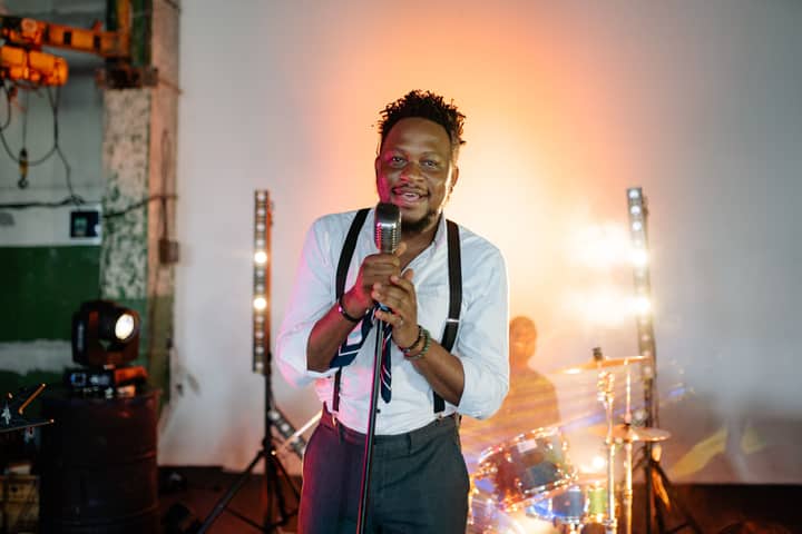 A charismatic male singer performing passionately on stage with vibrant lights.