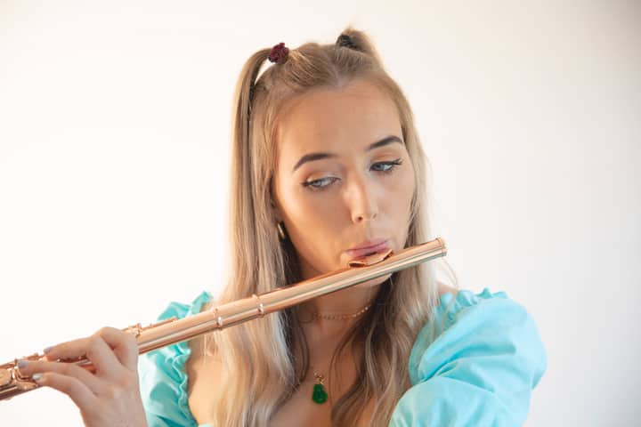 Close-up of a blonde woman playing the flute, showcasing musical talent and elegance.