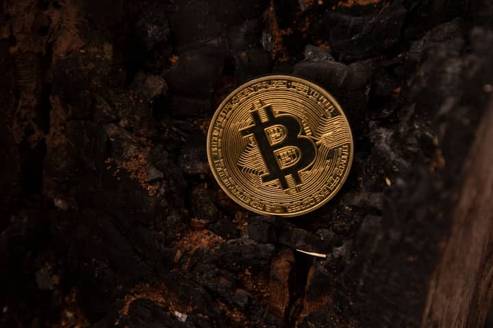 Detailed image of a Bitcoin coin placed on a charred, burnt background, symbolizing the rise of cryptocurrency.