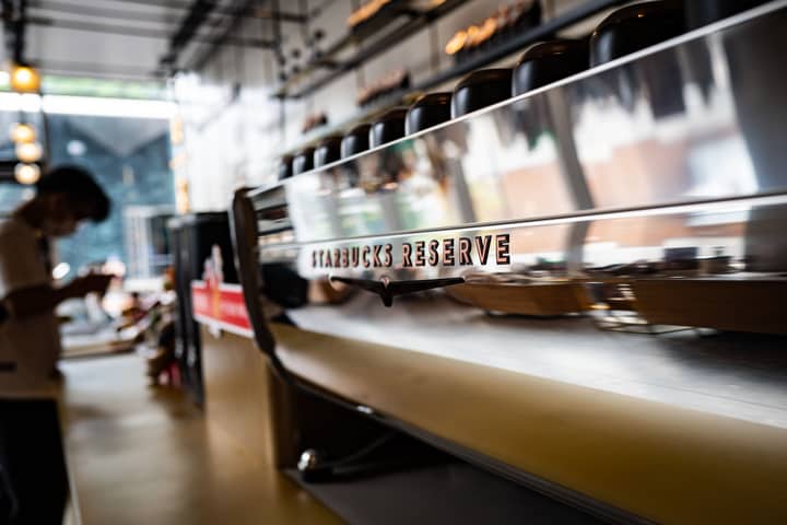 Contemporary Starbucks Reserve coffeeshop interior featuring a sleek espresso machine with a reflective surface.