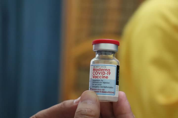 Detailed view of a Moderna COVID-19 vaccine vial held in hand, highlighting immunization efforts.