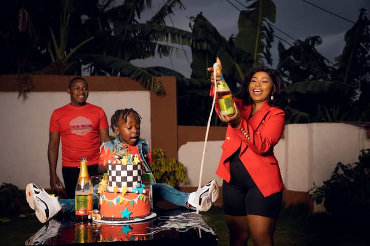 A joyful birthday celebration outdoors with family, featuring a colorful cake and sparkling drinks.