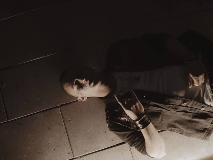 Stylish portrait of a man with a face tattoo lying on a pavement.