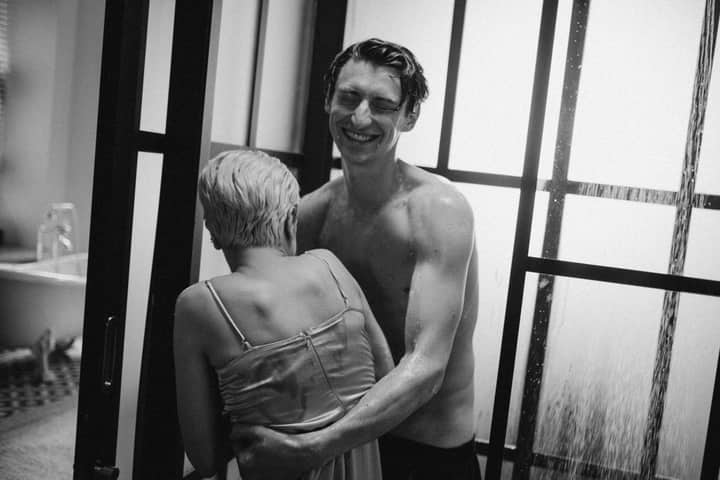 A joyful couple embraces in a shower, captured in a black and white, intimate setting.
