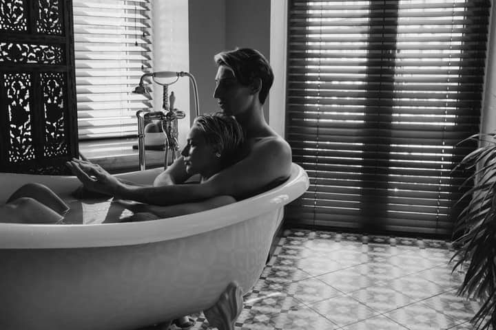 Black and white photo of a couple embracing in a bathtub, capturing a moment of intimacy and love.
