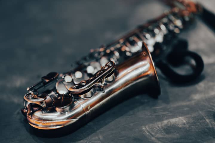 Detailed shot of a saxophone showcasing its shiny brass body against a blurred dark background.