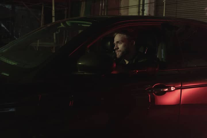 Man driving a car at night with retro lighting, capturing a moody and nostalgic vibe.