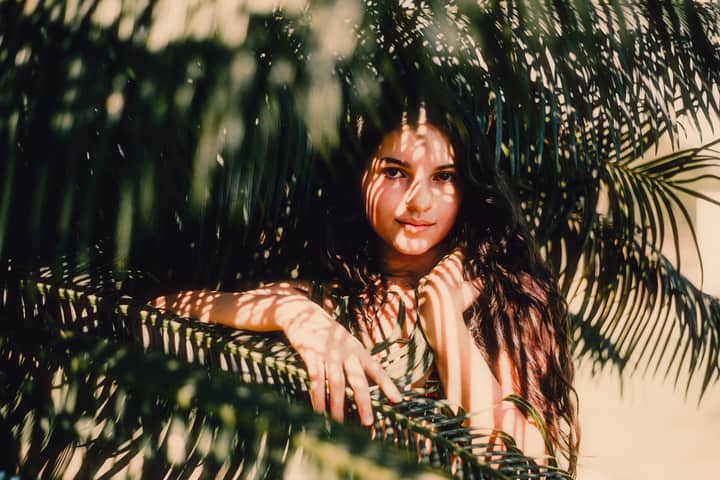 Portrait of a young woman with shadow patterns from palm leaves in Goiânia, Brazil, evoking warmth and natural beauty.