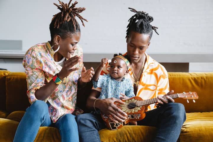 A joyful family moment with parents and child enjoying music and laughter.