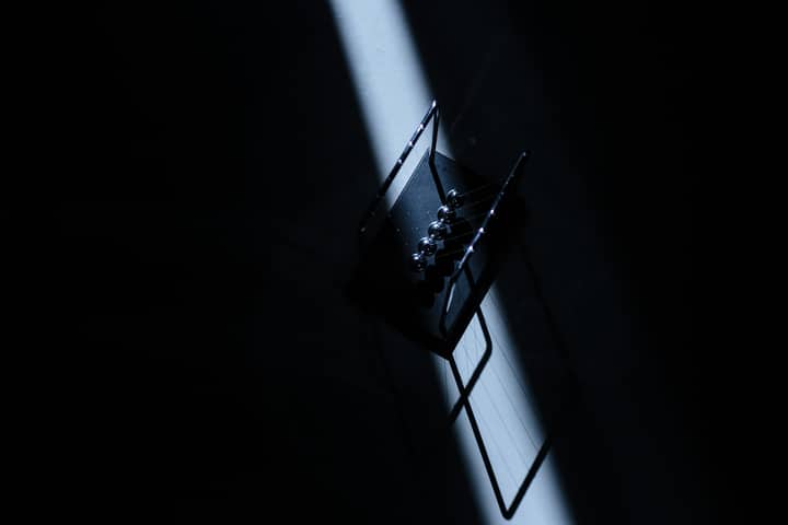 Newton's cradle in a dark room with striking light, showcasing physics concepts.