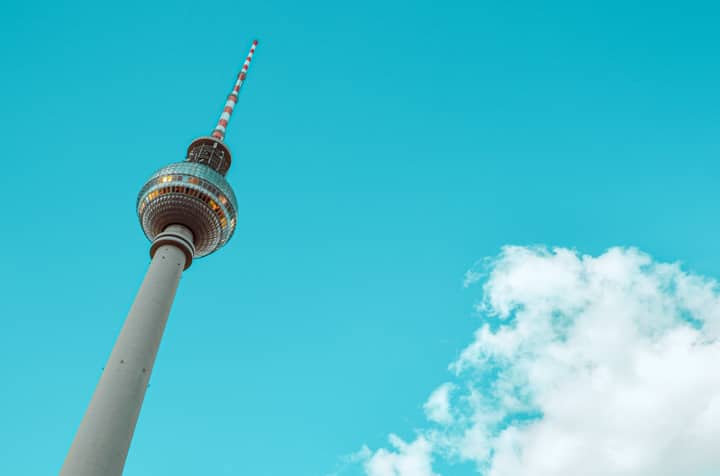 Low angle shot of Berlin's Fernsehturm with a vivid blue sky and clouds.
